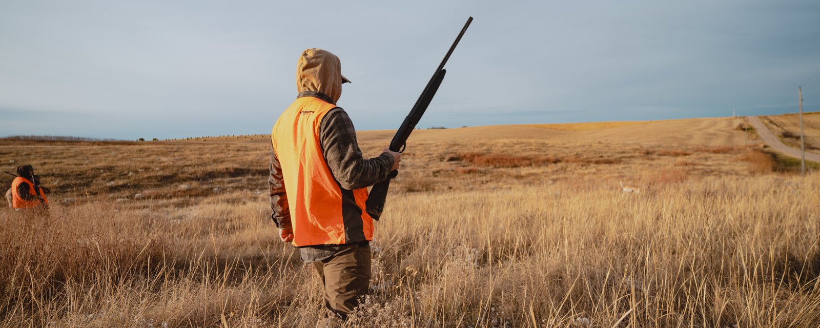 Hunters walking a golden prairie field at first light